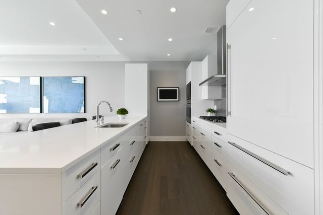 a large white kitchen with kitchen island white cabinets and stainless steel appliances
