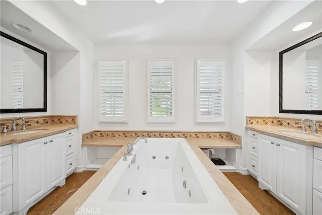 a spacious bathroom with a tub a sink and a large mirror