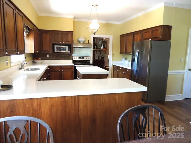 a kitchen with stainless steel appliances a refrigerator a stove a sink dishwasher with a dining table and chairs