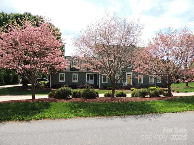 a front view of a house with a garden and trees