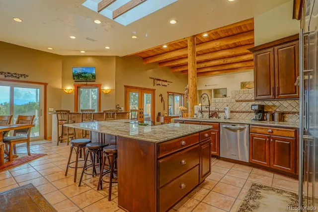 a kitchen with stainless steel appliances granite countertop a stove kitchen island a dining table and chairs