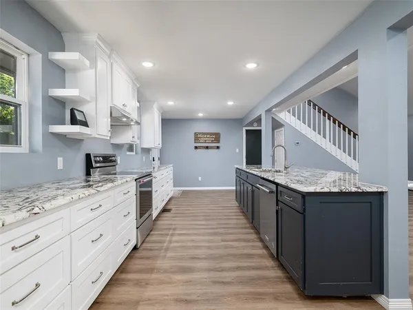 a large kitchen with stainless steel appliances granite countertop a lot of counter space and wooden floors