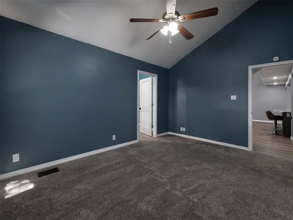 an empty room with a chandelier fan and windows