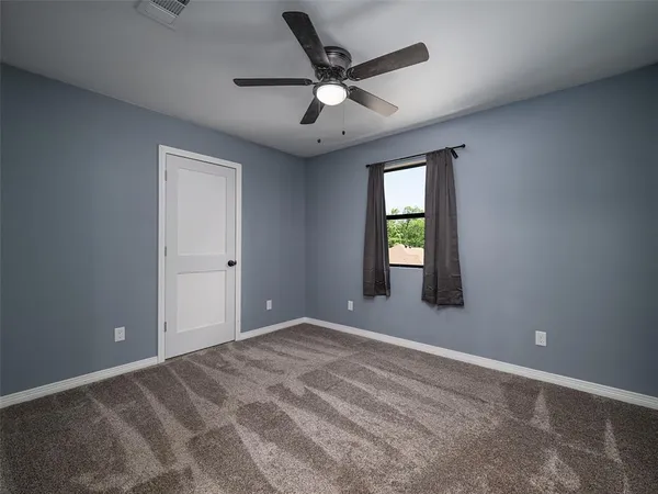 an empty room with windows and ceiling fan