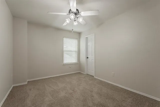 an empty room with a chandelier fan and windows