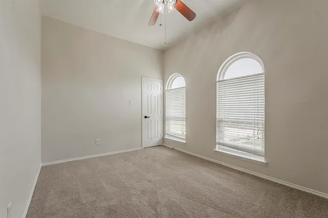 an empty room with windows and ceiling fan