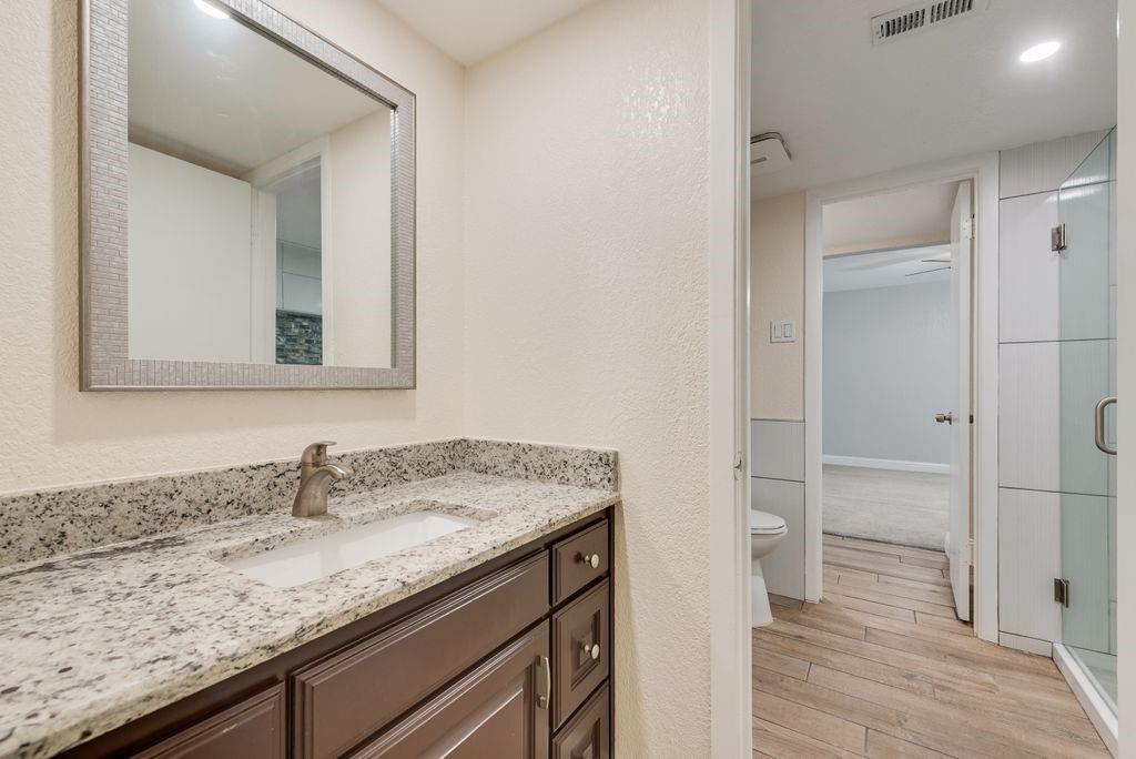 219 West Rochelle Road Irving, TX 75062 - Photo 22 of 29 Bathroom vanity featuring a light-toned granite countertop with an undermount sink and a brushed nickel faucet