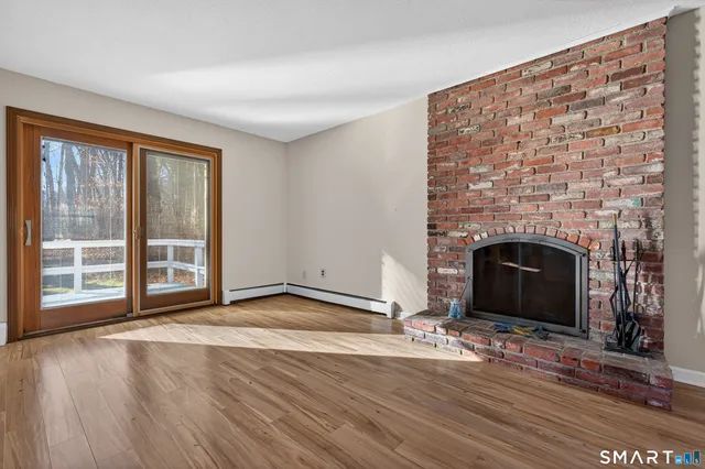 a view of empty room with wooden floor and fireplace