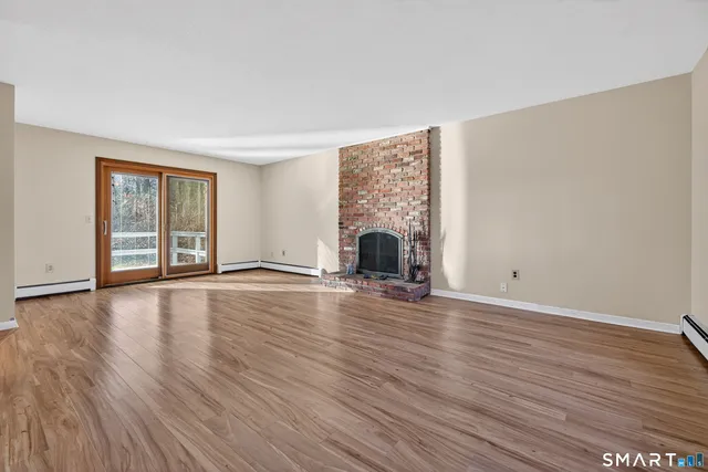 a view of empty room with wooden floor and fireplace