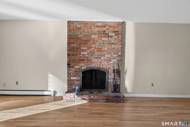 a view of empty room with wooden floor and fireplace