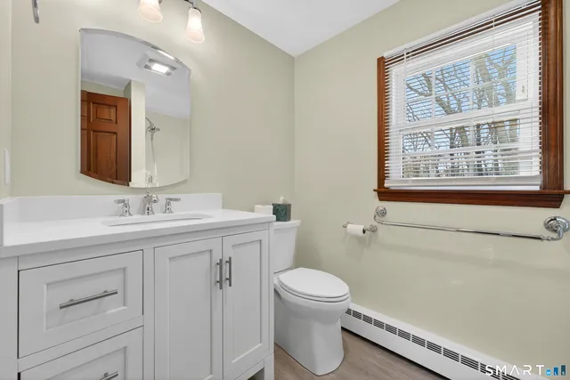 a bathroom with a granite countertop sink toilet and mirror