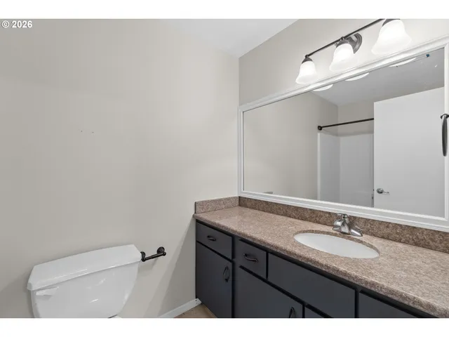 a bathroom with a granite countertop sink a toilet and a mirror