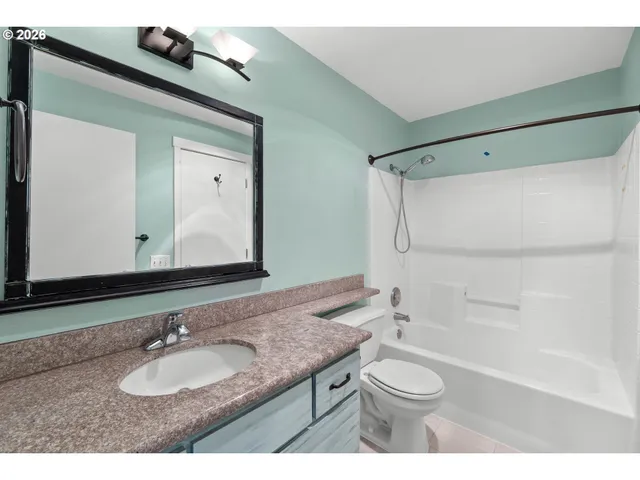 a bathroom with a granite countertop sink toilet a mirror and shower