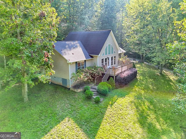 a view of a house with a big yard plants and large trees