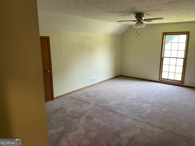 an empty room with windows and ceiling fan