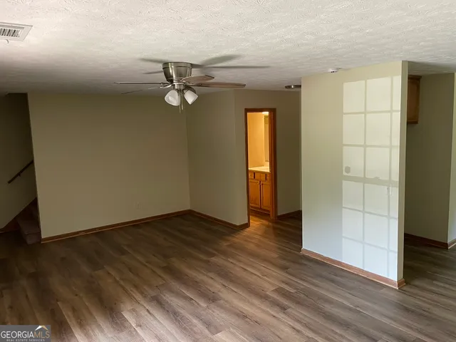 an empty room with wooden floor closet and windows