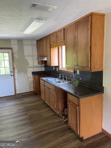 a kitchen with granite countertop a sink cabinets and wooden floor