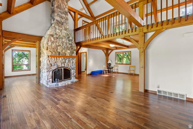 435 Canyon Road Millville, UT 84326 - Photo 9 of 113 Great room featuring a stone fireplace with a raised hearth, wood-finish flooring, exposed wood beams, and a second-story wood railing