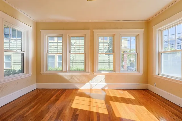 a view of an empty room with a window and wooden floor