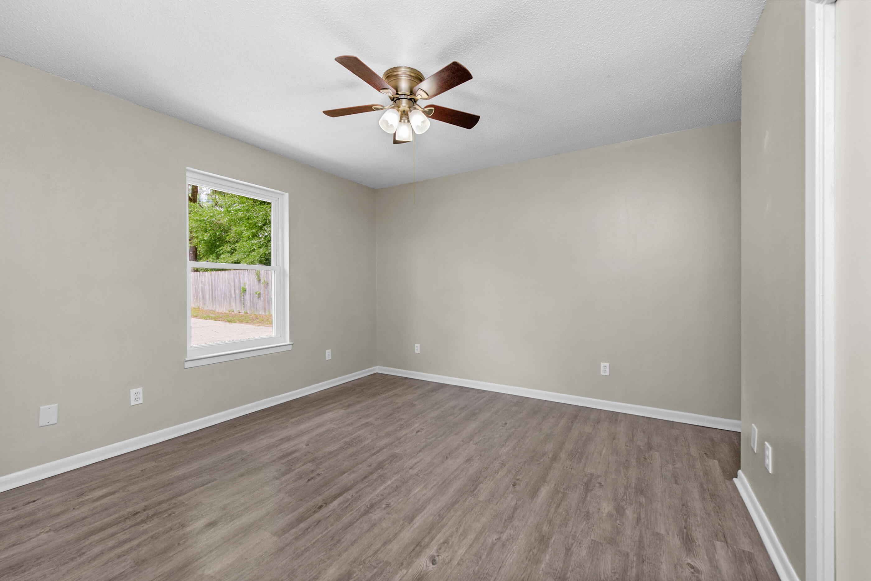 2909 Aplin Road Crestview, FL 32539 - Photo 18 of 29 an empty room with wooden floor chandelier fan and windows