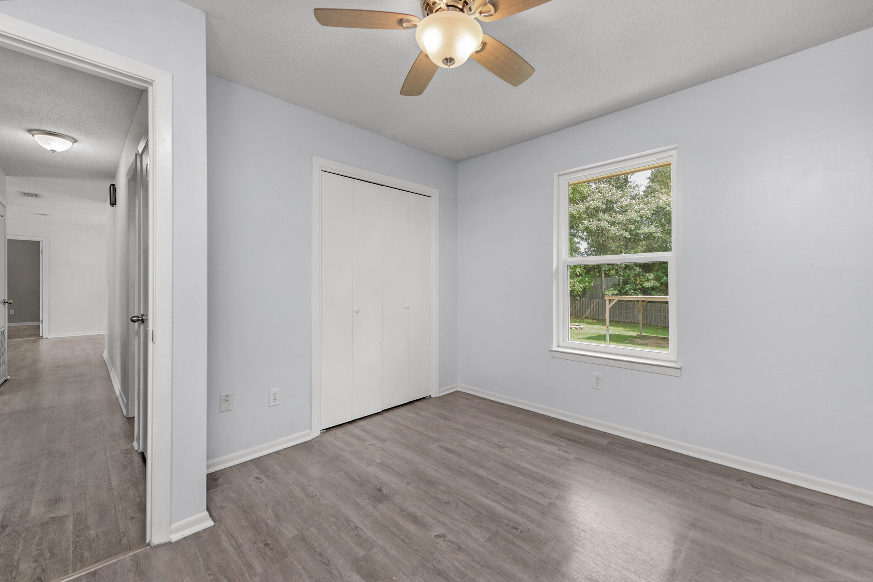 2909 Aplin Road Crestview, FL 32539 - Photo 21 of 29 an empty room with wooden floor fan and windows