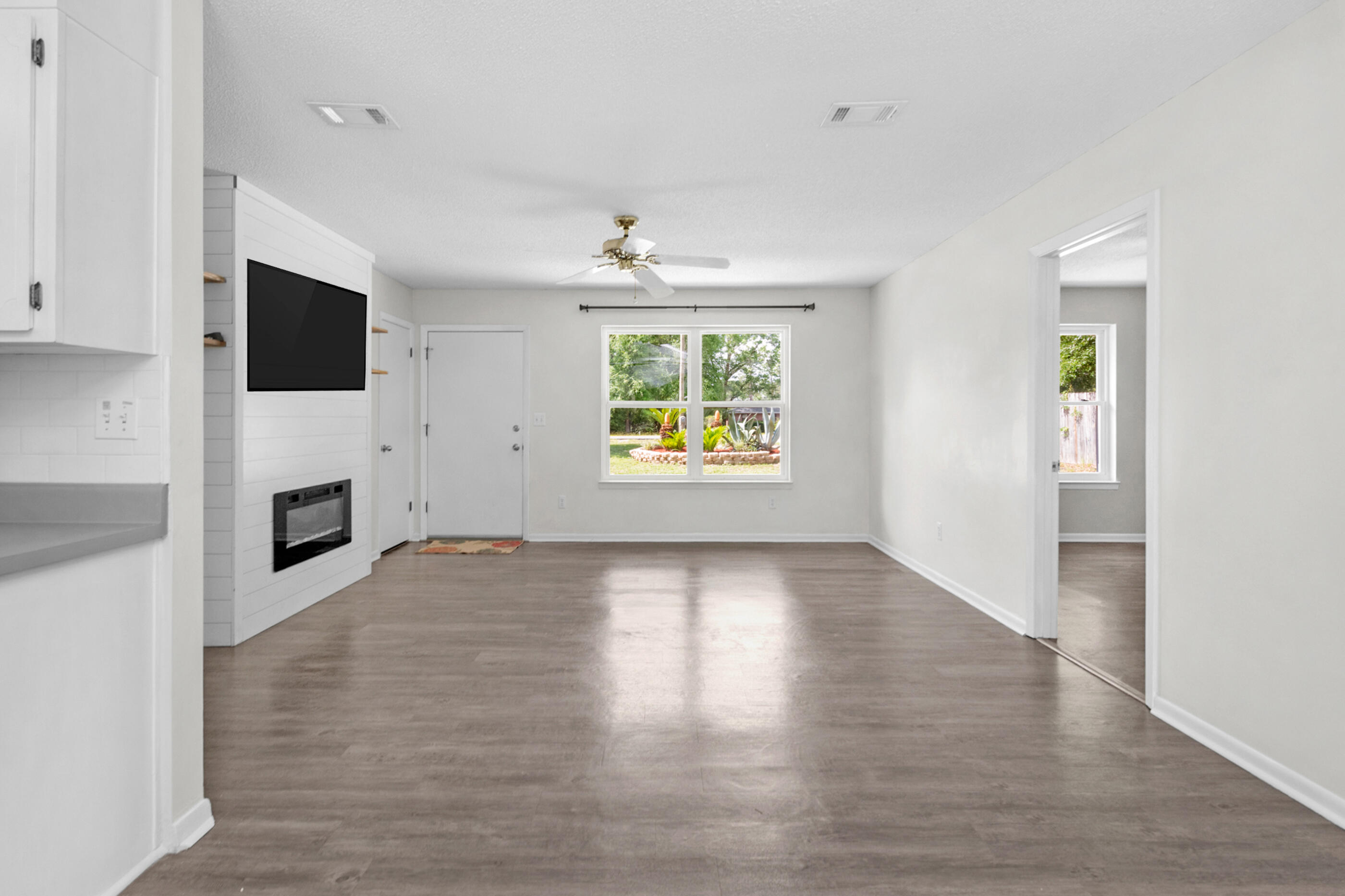 2909 Aplin Road Crestview, FL 32539 - Photo 10 of 29 an empty room with windows fireplace and wooden floor
