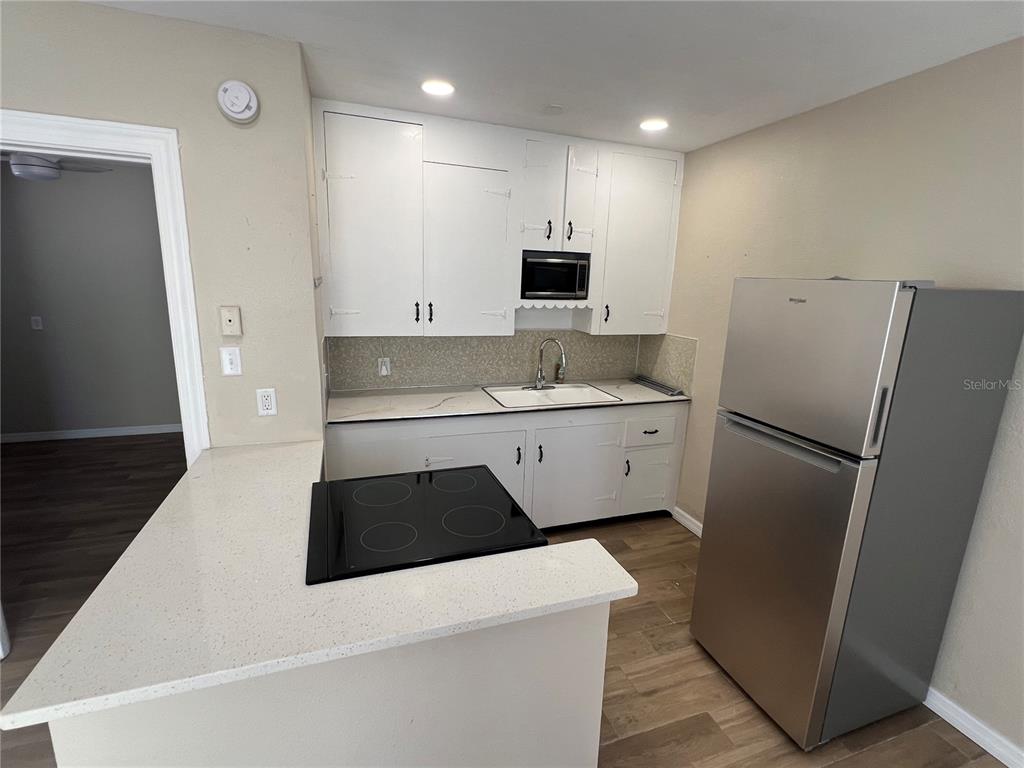 116 145th Avenue Madeira Beach, FL 33708 - Photo 4 of 17 a kitchen with stainless steel appliances a refrigerator sink and microwave