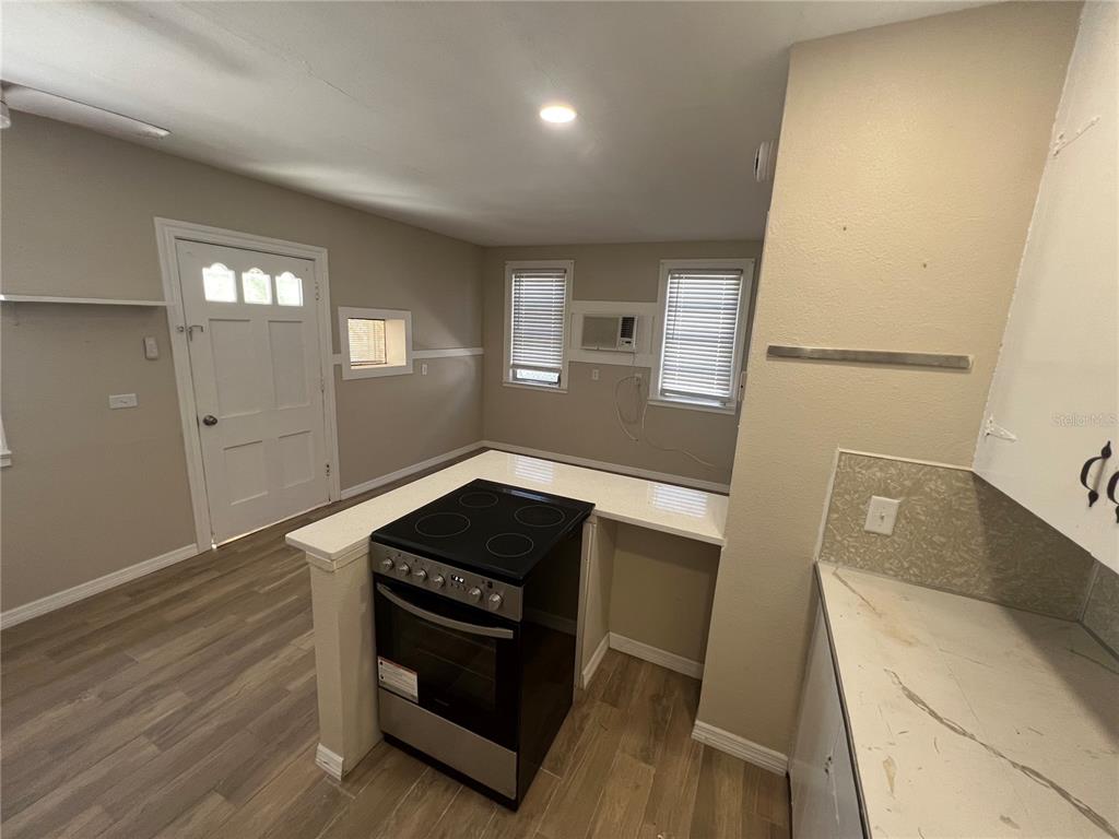 116 145th Avenue Madeira Beach, FL 33708 - Photo 6 of 17 a kitchen with wooden floor and black white cabinets