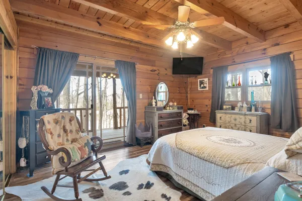 a spacious bedroom with a bed a flat screen tv and balcony view