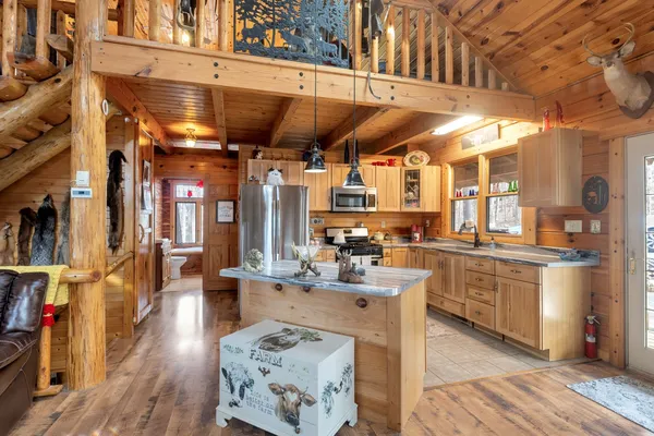 a kitchen with stainless steel appliances kitchen island granite countertop a table chairs in it and wooden floors