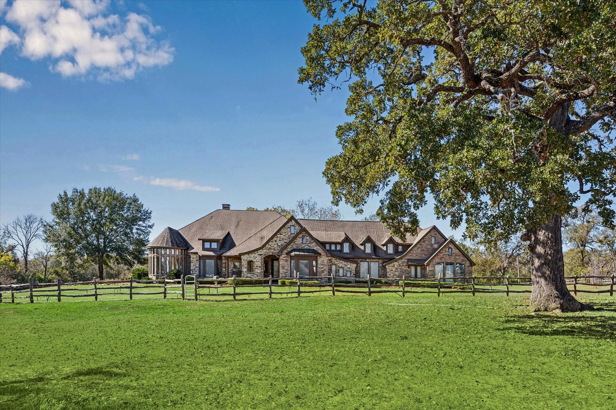 a view of a big house with a big yard and large trees