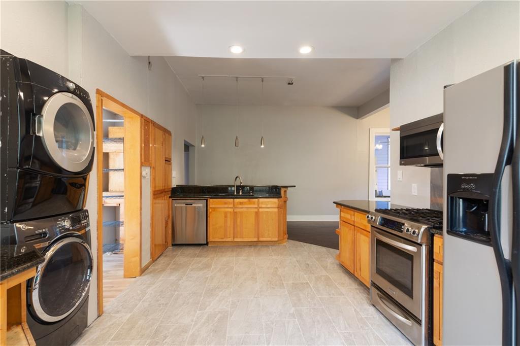 3210 Hampton Road, Unit A B C Austin, TX 78705 - Photo 25 of 42 Open-concept kitchen featuring light wood cabinetry, dark countertops, and stainless steel appliances