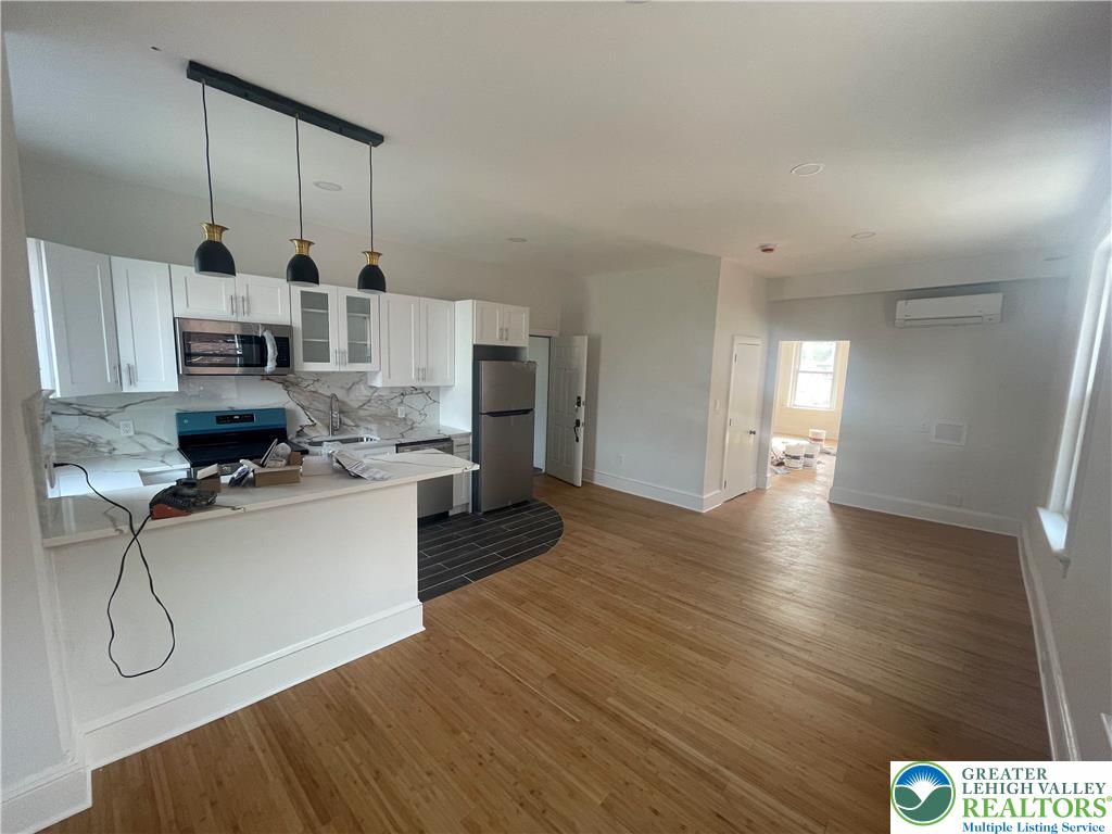 701 Main Street, Unit 2 Slatington, PA 18080 - Photo 4 of 11 a open kitchen with stainless steel appliances granite countertop a stove and white cabinets with wooden floor