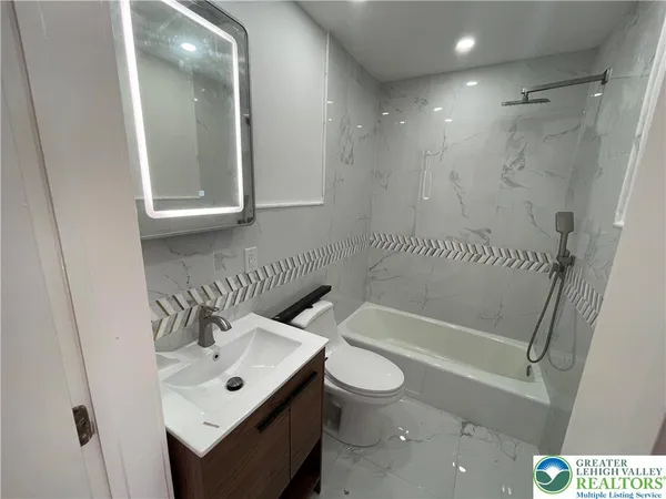 a bathroom with a bathtub shower sink vanity and toilet