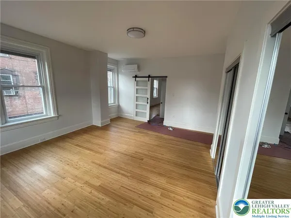 an empty room with wooden floor and windows