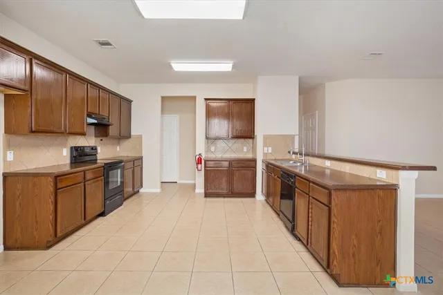 a large kitchen with stainless steel appliances granite countertop a stove a sink dishwasher and a refrigerator