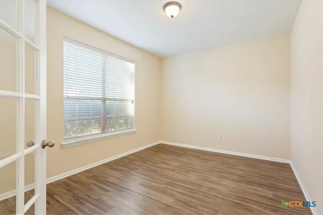 an empty room with wooden floor and windows