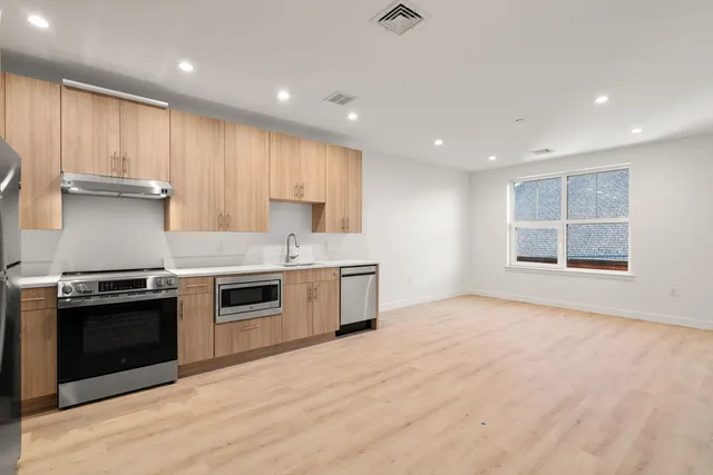 a large kitchen with stainless steel appliances granite countertop a stove a sink and a refrigerator