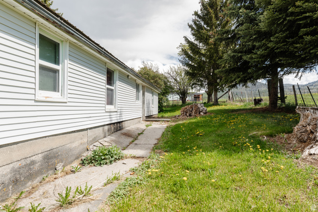 6746 North Capitol Hill Road Preston, ID 83263 - Photo 13 of 18 White siding exterior with multiple windows, concrete foundation, and a concrete pathway