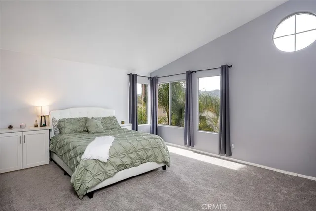 a bedroom with a bed lamp and a large window