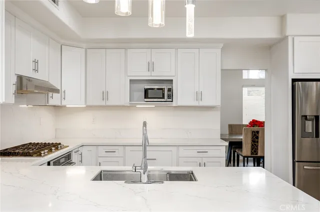 a kitchen with kitchen island a stove a sink and a white cabinets