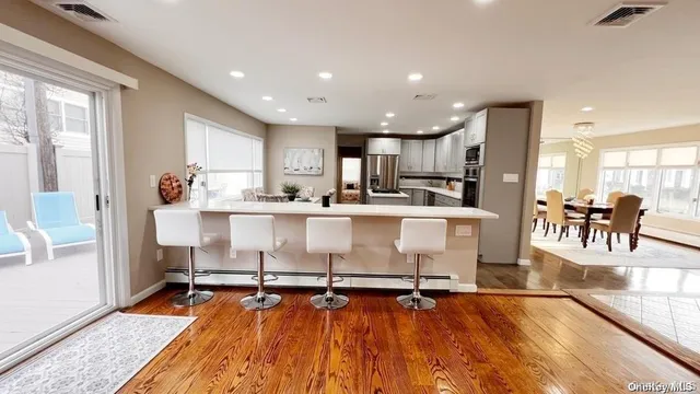 a living room with stainless steel appliances kitchen island granite countertop wooden floor dining table and chairs