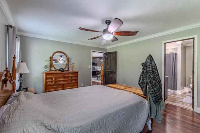 a bedroom with a bed and dresser with wooden floor
