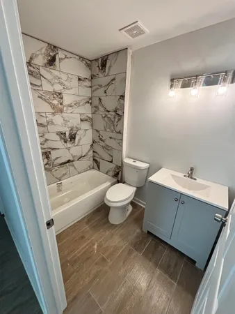 a bathroom with a bathtub shower sink mirror and toilet