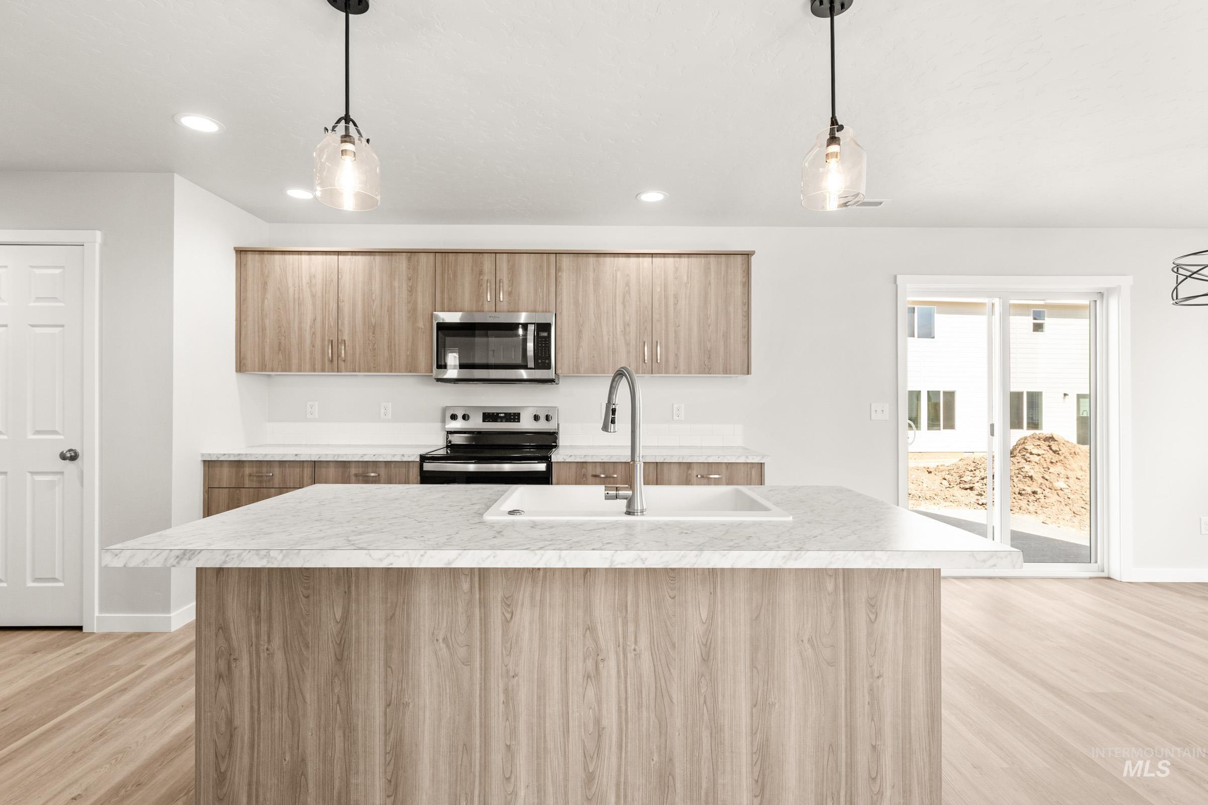 13716 Redway Court Caldwell, ID 83607 - Photo 2 of 18 Kitchen featuring light countertops, hanging light fixtures, stainless steel appliances, and light wood-style flooring