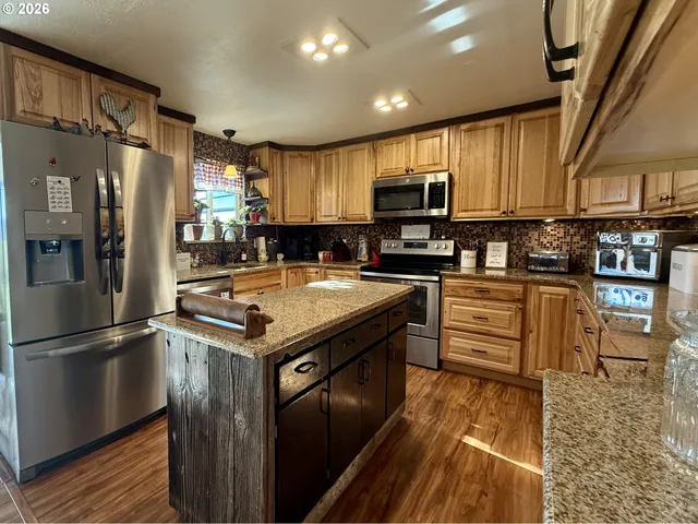 a kitchen with stainless steel appliances granite countertop wooden cabinets a stove top oven a sink and dishwasher