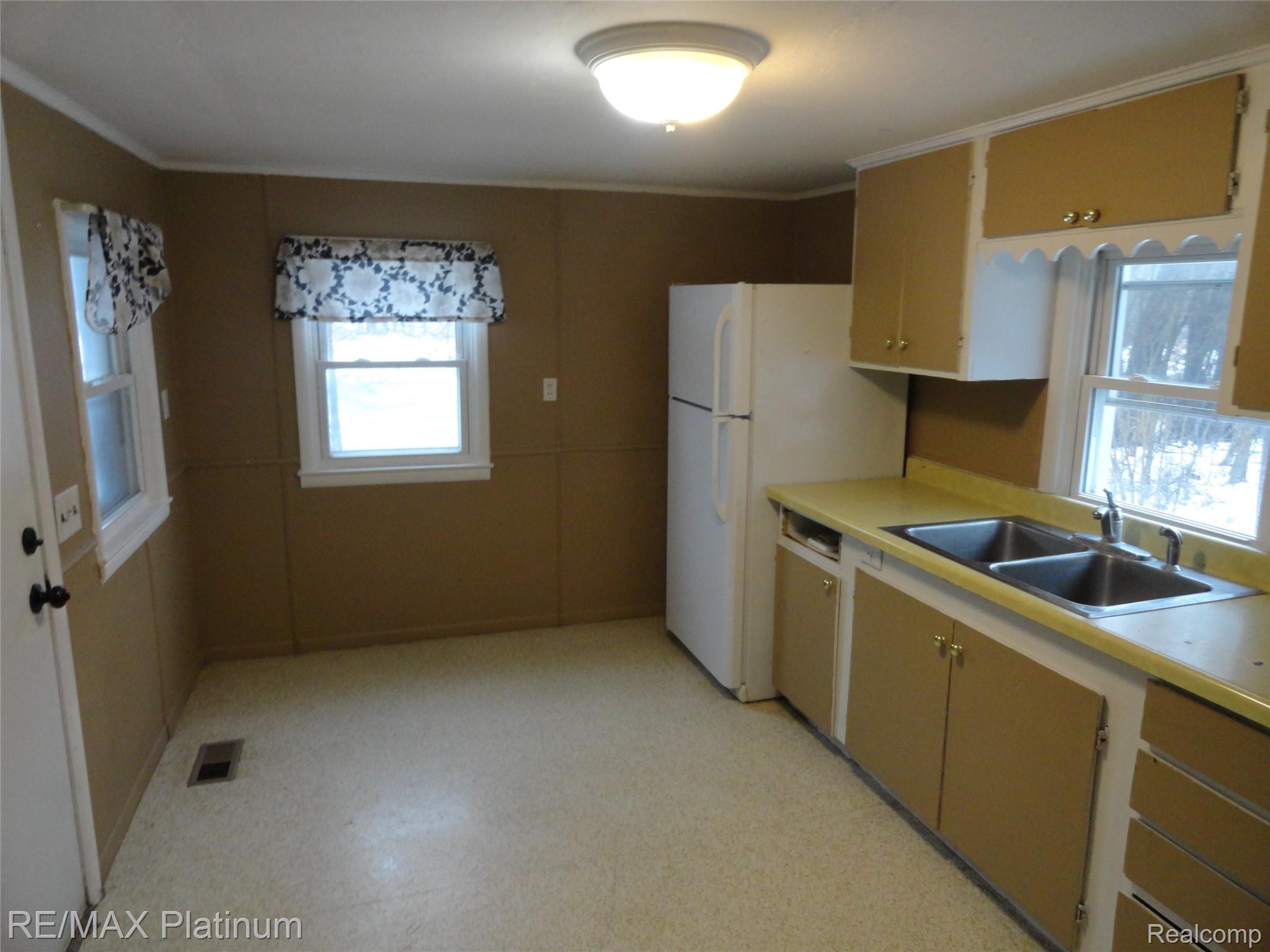 Kitchen featuring light flooring, light countertops, and freestanding refrigerator