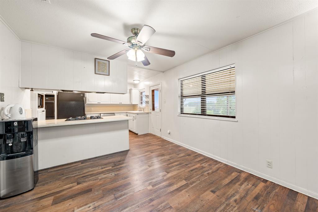 608 West Spring Street West, TX 76691 - Photo 10 of 23 Wood-finish flooring, white panel walls, and a ceiling fan with light fixture