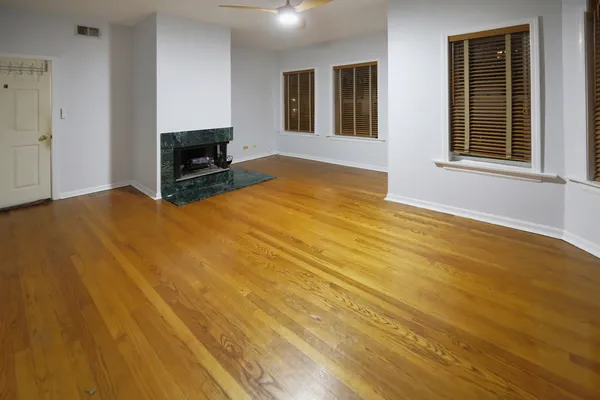 a view of empty room with wooden floor and fireplace