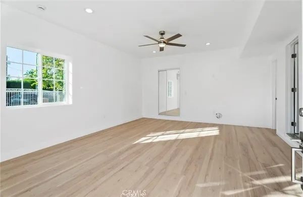 a view of empty room with wooden floor and fan
